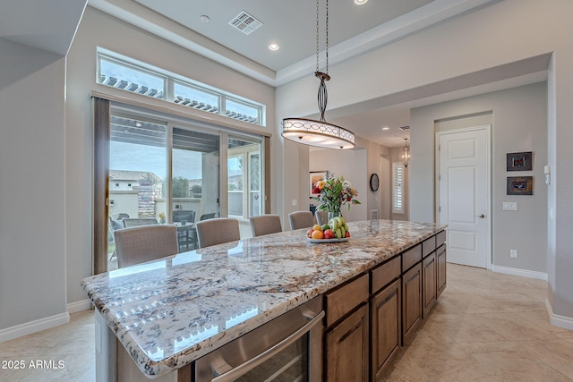 kitchen with hanging light fixtures, a center island, light stone countertops, light tile patterned flooring, and beverage cooler