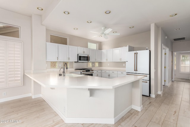 kitchen with sink, kitchen peninsula, light hardwood / wood-style floors, stainless steel appliances, and white cabinets