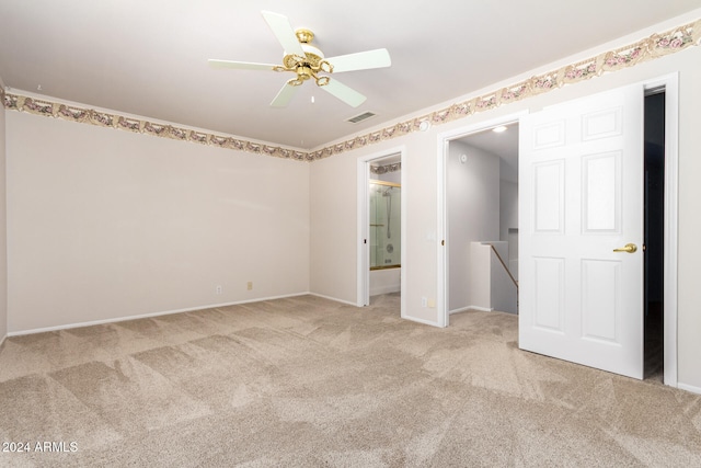 unfurnished bedroom with connected bathroom, light colored carpet, and ceiling fan