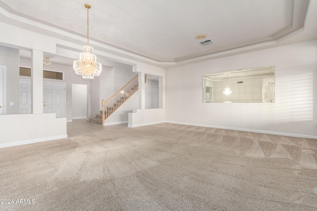 unfurnished living room featuring a notable chandelier, carpet flooring, and a raised ceiling