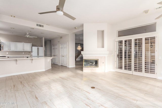 unfurnished living room featuring sink, light wood-type flooring, and ceiling fan