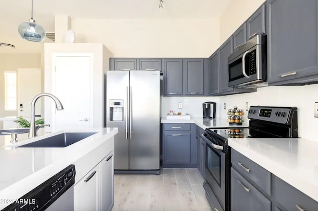 kitchen featuring gray cabinetry, appliances with stainless steel finishes, sink, hanging light fixtures, and light hardwood / wood-style flooring