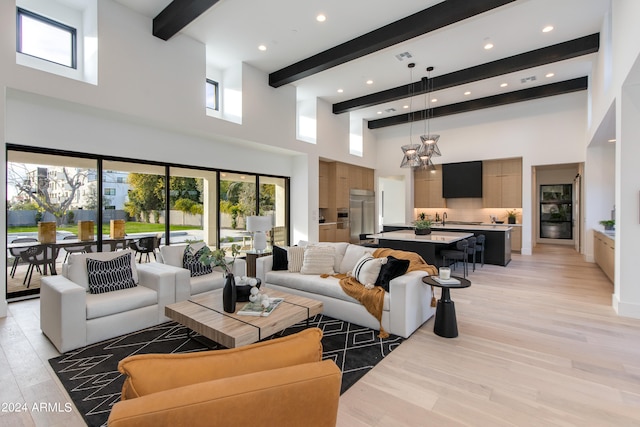 living room with a high ceiling, a chandelier, light hardwood / wood-style flooring, sink, and beam ceiling