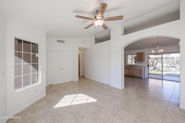 tiled spare room featuring lofted ceiling, sink, and ceiling fan with notable chandelier