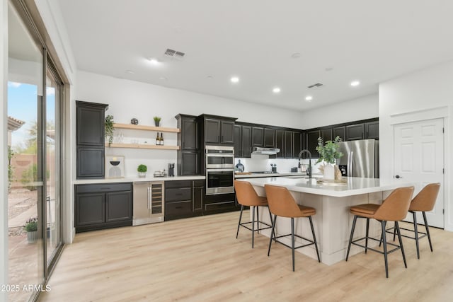 kitchen with visible vents, under cabinet range hood, light countertops, appliances with stainless steel finishes, and a sink