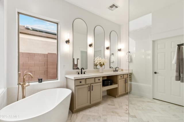 full bath featuring double vanity, a freestanding tub, visible vents, and a sink