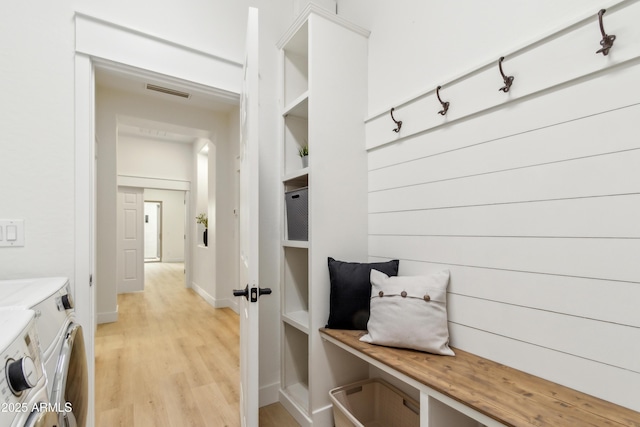 mudroom featuring light wood finished floors, visible vents, washing machine and dryer, and baseboards