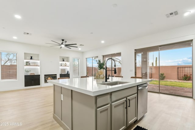 kitchen featuring dishwasher, gray cabinetry, visible vents, and a sink