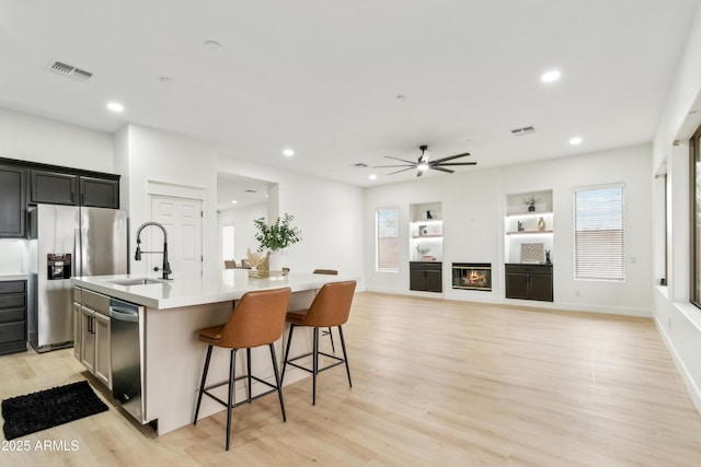 kitchen with visible vents, appliances with stainless steel finishes, an island with sink, and a sink