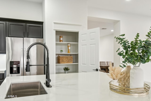 kitchen featuring visible vents, a sink, recessed lighting, stainless steel fridge with ice dispenser, and light stone countertops