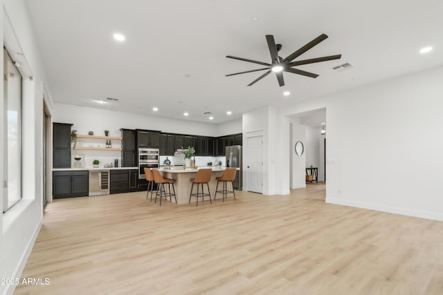 kitchen with visible vents, wine cooler, a breakfast bar area, light countertops, and appliances with stainless steel finishes