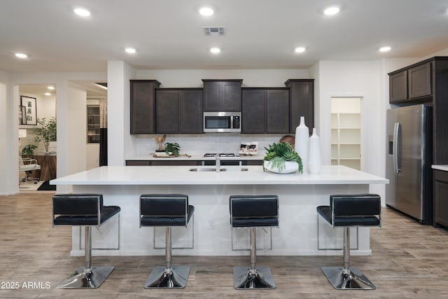 kitchen featuring a center island with sink, a kitchen bar, and stainless steel appliances