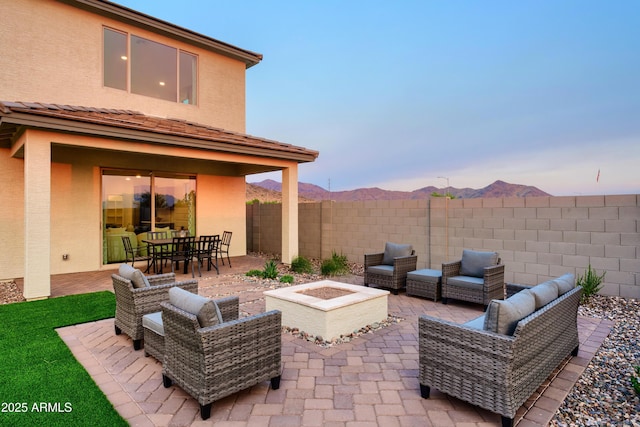 patio terrace at dusk with a mountain view and an outdoor living space with a fire pit