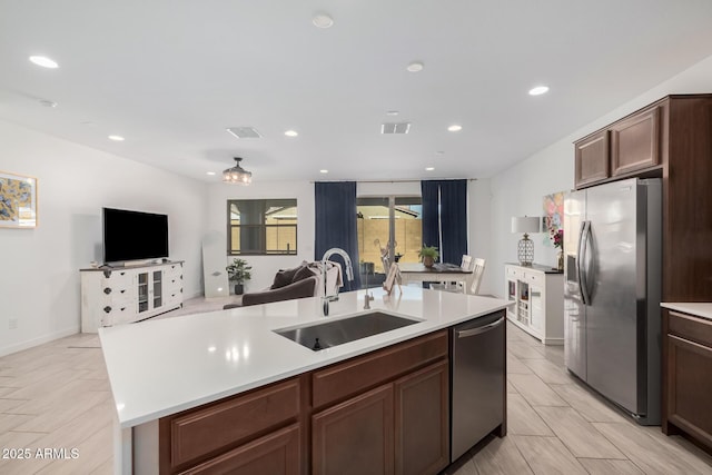 kitchen with appliances with stainless steel finishes, sink, a center island with sink, and dark brown cabinets