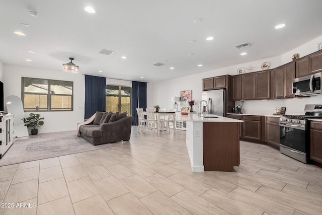 kitchen featuring stainless steel appliances, a kitchen island with sink, sink, and dark brown cabinetry