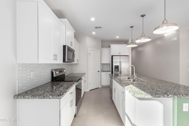 kitchen with appliances with stainless steel finishes, pendant lighting, white cabinetry, sink, and a kitchen island with sink