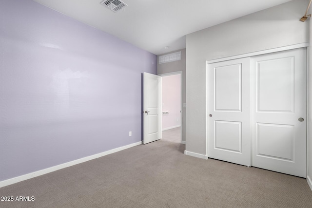 unfurnished bedroom with light colored carpet and a closet