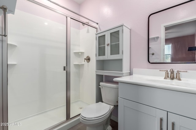 bathroom with vanity, a shower with shower door, and toilet