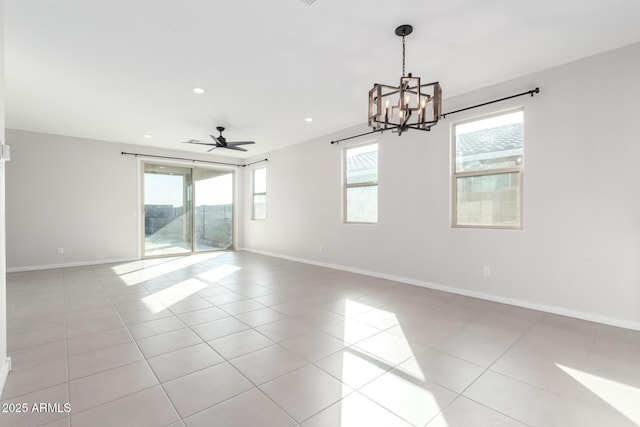 tiled spare room featuring a healthy amount of sunlight and ceiling fan with notable chandelier