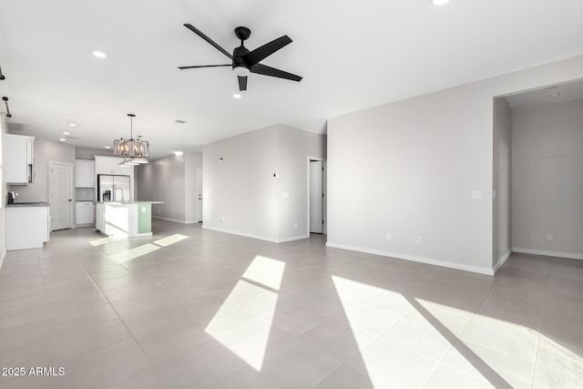 unfurnished living room featuring light tile patterned floors and ceiling fan with notable chandelier