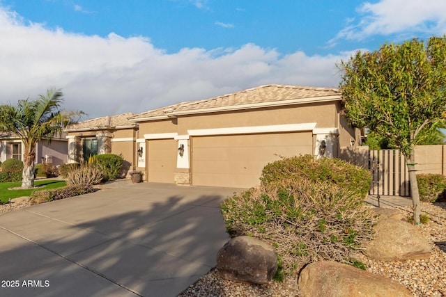 view of front facade featuring driveway, a tile roof, stucco siding, fence, and an attached garage