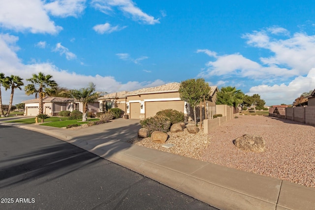 view of front of house with fence, a garage, concrete driveway, a residential view, and stucco siding