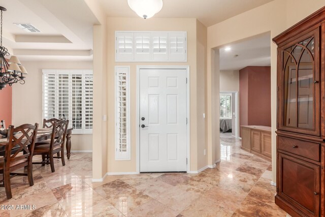 foyer with a notable chandelier, baseboards, and visible vents