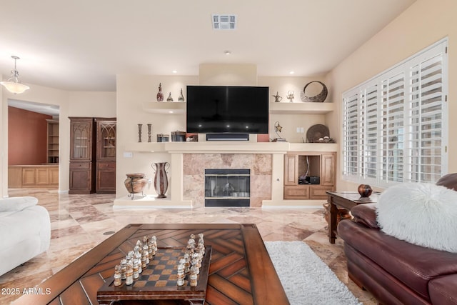 living area with marble finish floor, visible vents, built in features, and a fireplace