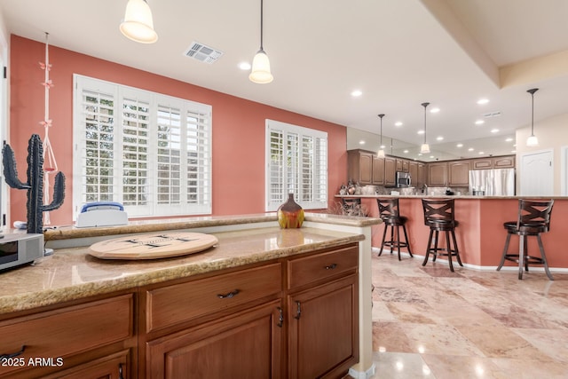kitchen with visible vents, a breakfast bar area, pendant lighting, and stainless steel appliances