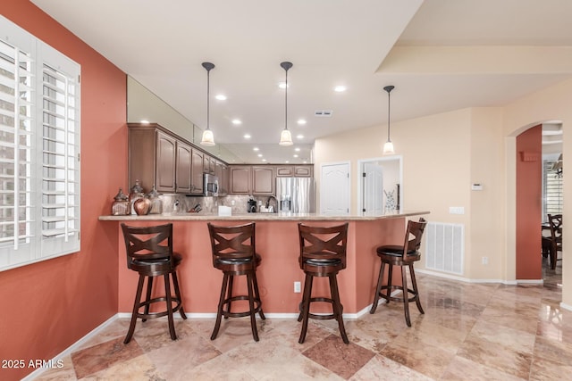 kitchen with arched walkways, visible vents, a peninsula, and appliances with stainless steel finishes