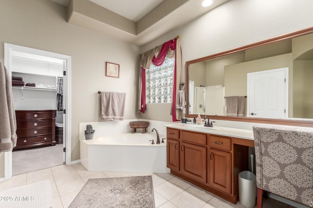 full bathroom with tile patterned floors, vanity, a stall shower, a garden tub, and a walk in closet