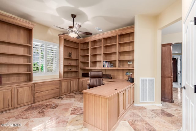 unfurnished office with built in desk, ceiling fan, and visible vents