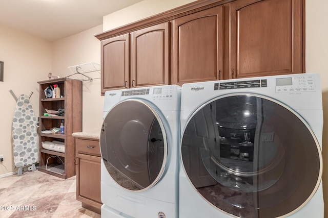 clothes washing area featuring washing machine and dryer and cabinet space