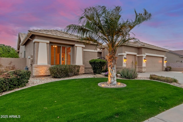 prairie-style house with a front lawn, stucco siding, an attached garage, and stone siding