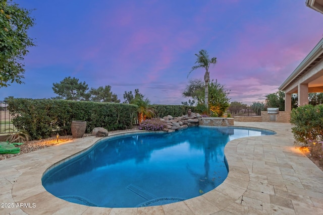 pool at dusk with a patio, fence, a fenced in pool, and area for grilling