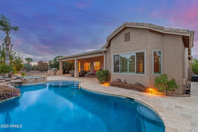 back of property with stucco siding, a pool with connected hot tub, a ceiling fan, and a patio area