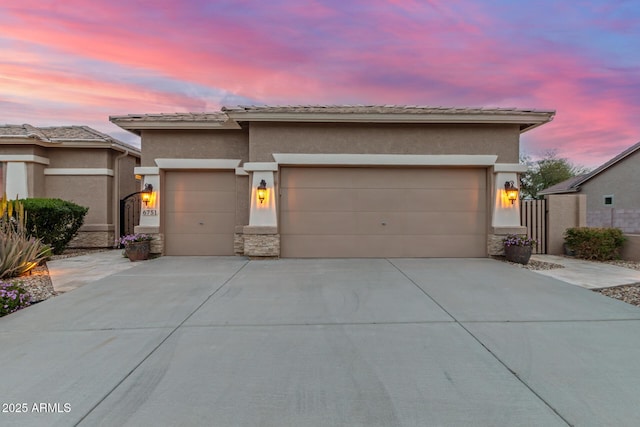 prairie-style house with driveway, stucco siding, and an attached garage