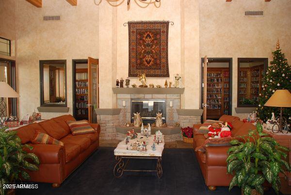 living room with visible vents, a high ceiling, and a glass covered fireplace