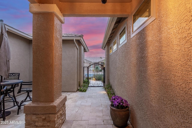 patio terrace at dusk featuring a gate and outdoor dining area