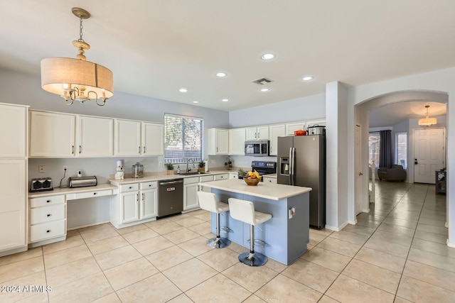 kitchen with pendant lighting, a center island, black appliances, white cabinets, and light tile patterned floors