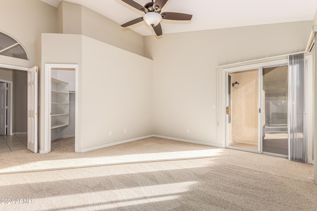 unfurnished bedroom with carpet, a closet, a spacious closet, and ceiling fan