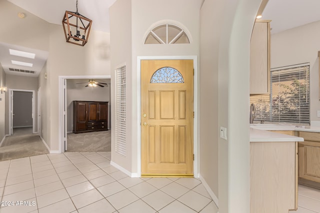 foyer entrance featuring light carpet, a towering ceiling, ceiling fan, and sink