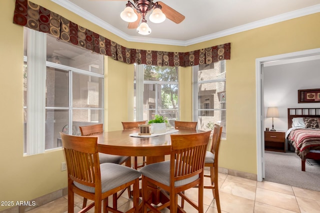 dining space with ornamental molding, light tile patterned flooring, a ceiling fan, and baseboards