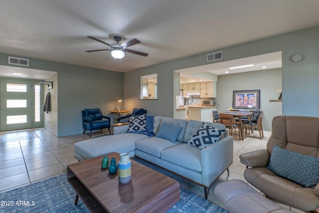 living room with light tile patterned floors, visible vents, and a ceiling fan