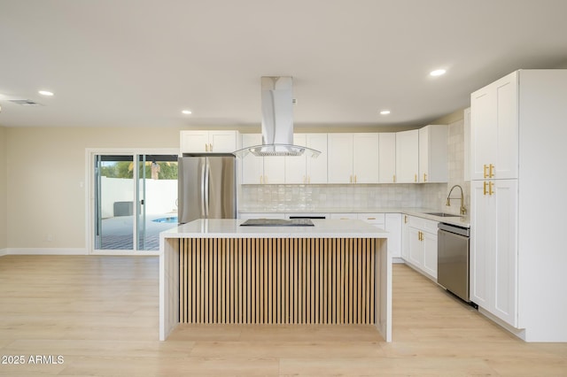 kitchen featuring white cabinets, appliances with stainless steel finishes, island exhaust hood, and a kitchen island