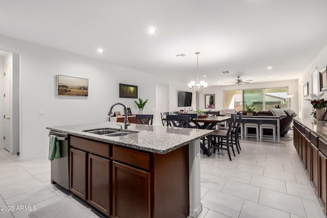 kitchen featuring decorative light fixtures, sink, stainless steel dishwasher, light stone countertops, and a center island with sink