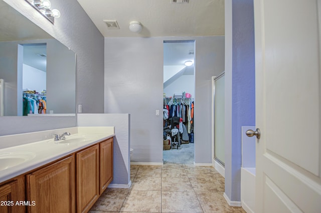 bathroom featuring tile patterned flooring, visible vents, double vanity, a stall shower, and a sink