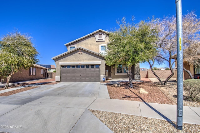 view of front facade featuring concrete driveway, an attached garage, fence, and stucco siding