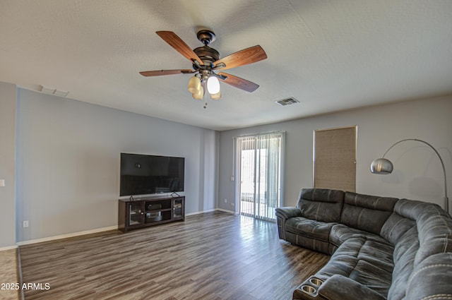 living room with visible vents, a textured ceiling, baseboards, and wood finished floors