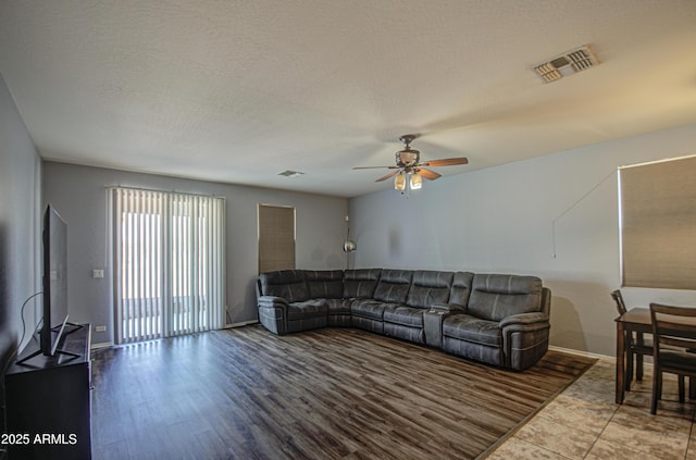 living area featuring visible vents, a textured ceiling, wood finished floors, and a ceiling fan